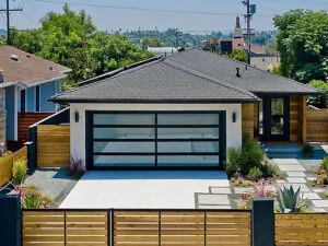 Stylish single-story modern home featuring a sleek glass-panel garage door that enhances curb appeal and natural light.