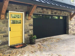 Modern Entryway with Yellow Door and Black Garage Door