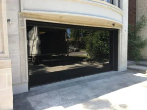Front view of a two-car garage with the door open, a pickup truck inside, and a stone-and-stucco facade.