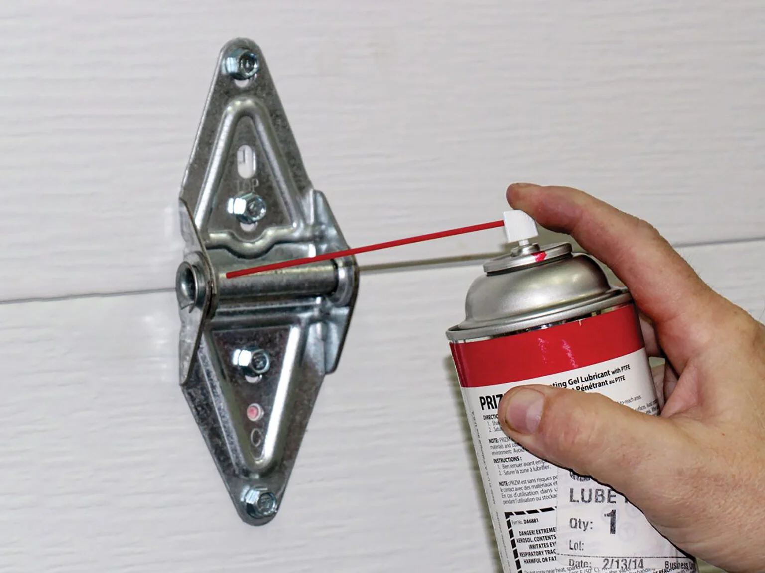 Professional applying lubricant to garage door hinges to maintain quiet, efficient, and long-lasting performance.