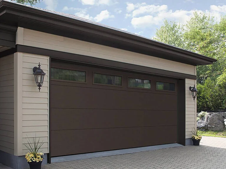 Brown sectional garage door with small rectangular transom windows at top.
